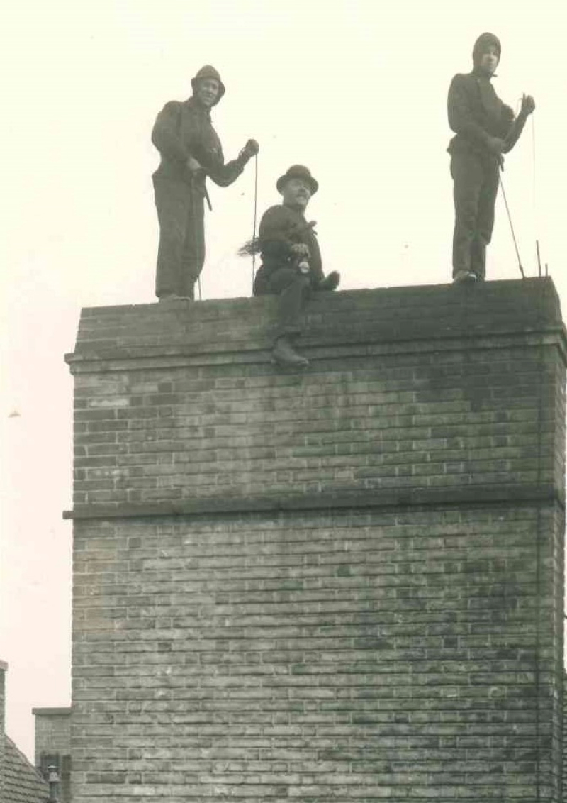 Kaminfeger bei der Arbeit auf dem Dach, historische Aufnahme
